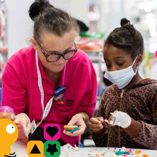Children in hospital playing with building bricks alongside a health play specialist